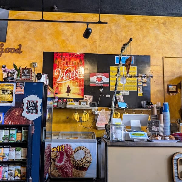 A vibrant cafe interior with a counter, display cases, and a person working behind the counter.