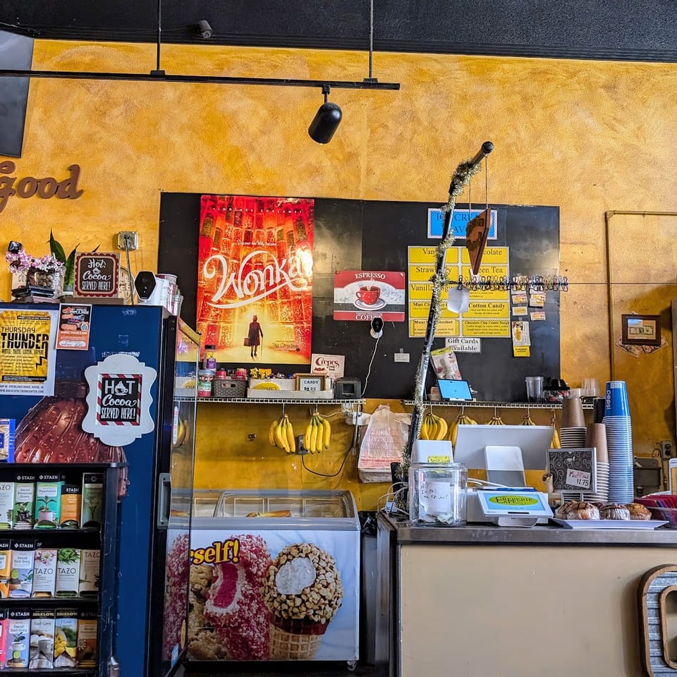 A vibrant cafe interior with a counter, display cases, and a person working behind the counter.